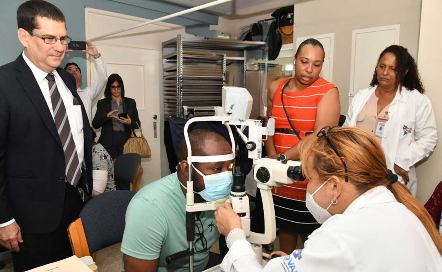 Cuban Ambassador Fermín Gabriel Quiñones, Programme Coordinator Natasha Biggs and Dr. Mayra Chaveco, Head of the Cuban eye team observe the examination of a patient.