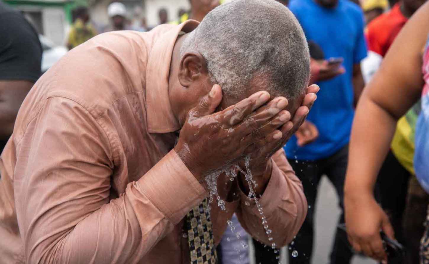 Western Kingston MP Desmond McKenzie washes his face after being pepper sprayed by the polic e in West Kingston on Tuesday.