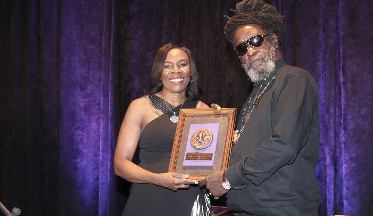 Leader of Jamaica's Reggae Grammy Award Winning group Black Uhuru Derrick 'Duckie’ Simpson accepts the Marcus Garvey Lifetime Achievement Award from an official of the Jamaican Embassy Mrs Gloria Davis-Simpson.