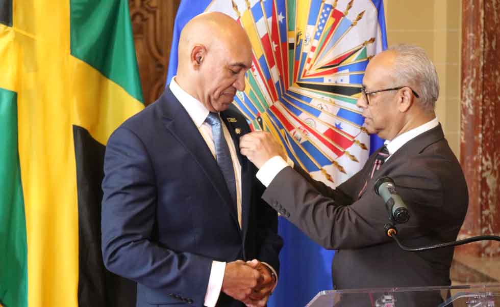 Ambassador Anthony Anderson is given an OAS lapel pin by OAS Secretary General Albert Ramdin. 