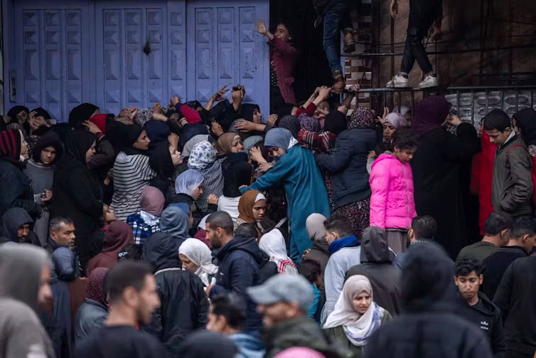 Palestinians try to buy bread from a bakery in Rafah, as food shortages continue to worsen. Fatima Shbair/AAP