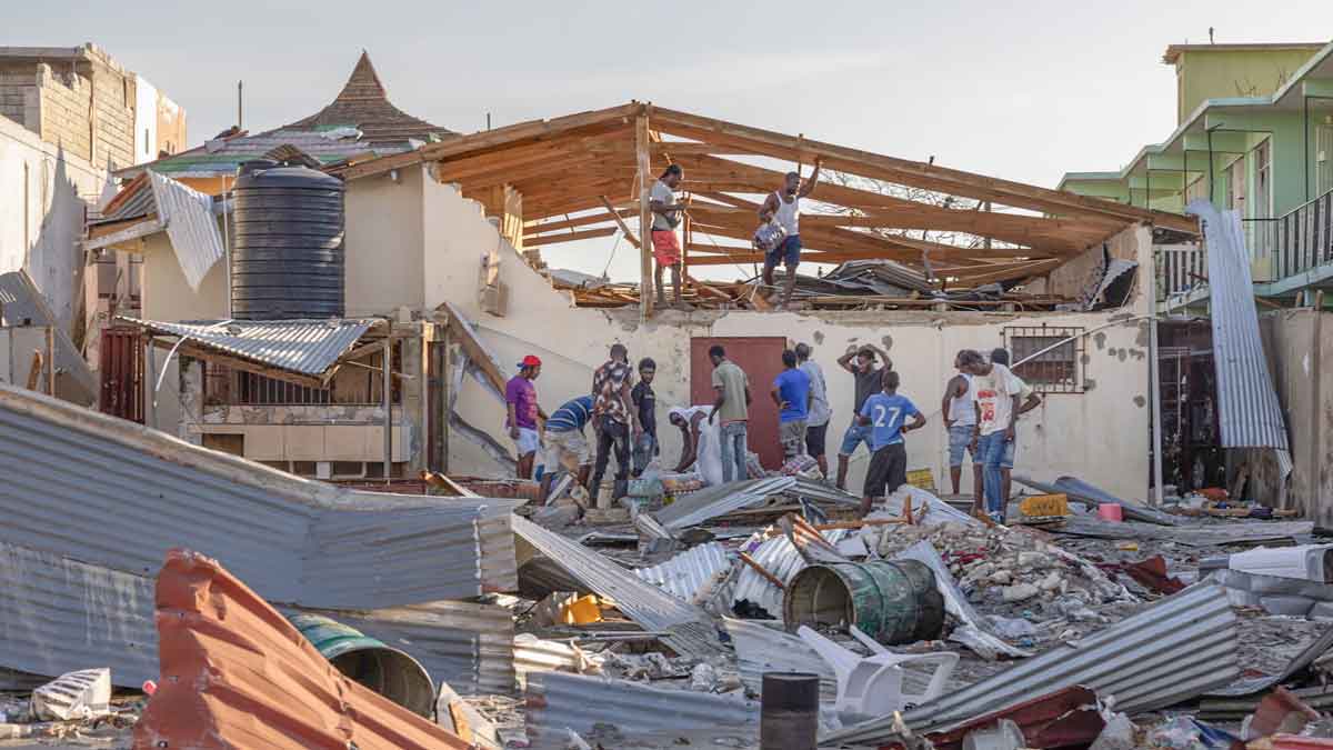 Men gather at a destroyed building after the passage of Hurricane Melissa. Photograph: Ina Sotirova/The Guardian