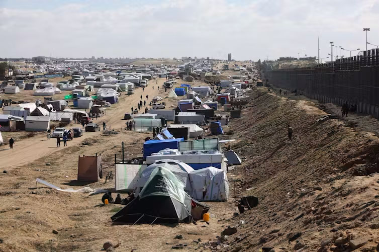 Palestinians shelter next to Gaza’s border fence with Egypt. Hatem Ali/AAP